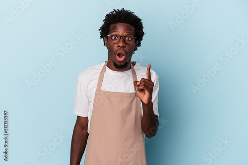 Foto Young african american store clerk isolated on blue background having an idea, inspiration concept