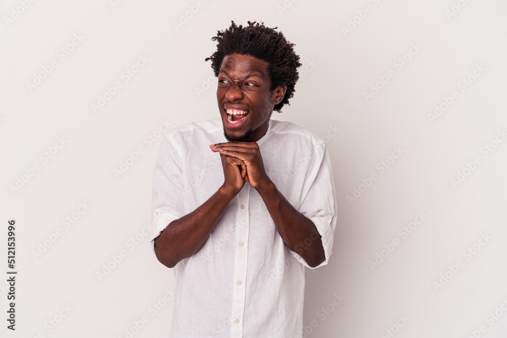 Young african american man isolated on white background keeps hands under chin, is looking happily aside. Young african american man isolated on white background keeps hands under chin, is looking happily aside.