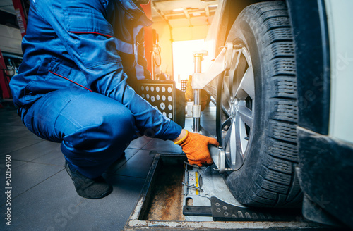 Auto mechanic installing sensor during suspension adjustment and automobile wheel alignment work at repair service station. Close up