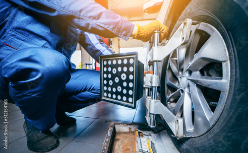 Canvas-taulu Auto mechanic installing sensor during suspension adjustment and automobile wheel alignment work at repair service station