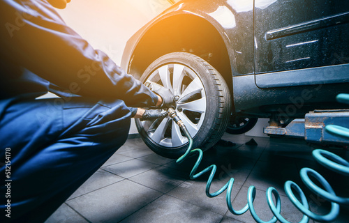 Hands of professional car mechanic changing car wheel in auto repair service. Close up	
 photo