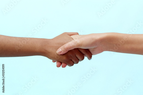 Caucasian and black African American woman shaking hands on a blue background. Racism concept and all lives matter