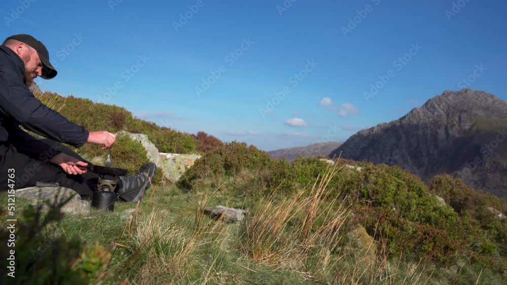 A man cooking steak in a frying pan overlooking the mountains A man cooking steak in a frying pan overlooking the mountains