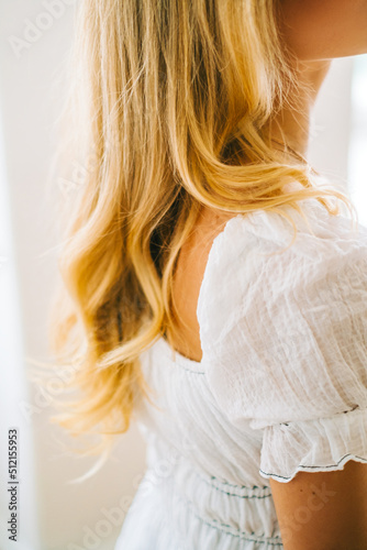Caucasian woman with blonde hair in white dress, close up hair curls
