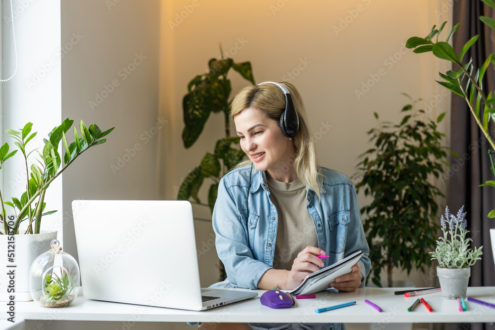 Photo of charming positive person sit behind desktop look use laptop have good mood working home indoors Photo of charming positive person sit behind desktop look use laptop have good mood working home indoors