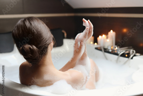 Tableau sur toile Young woman taking bubble bath, back view. Romantic atmosphere