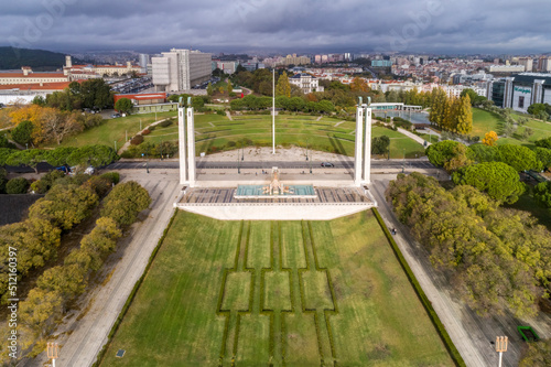 Aerial view of observation deck of Parque Eduardo VII or Park of Eduard the VII Sloped  scenic park featuring tree-lined walking paths  manicured lawns   distant water views in Lisbon 