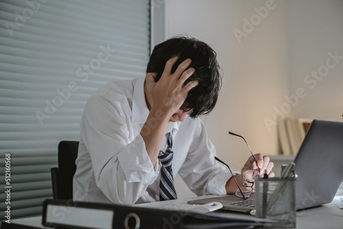 Asian stress business man tired and worried in office at late night.