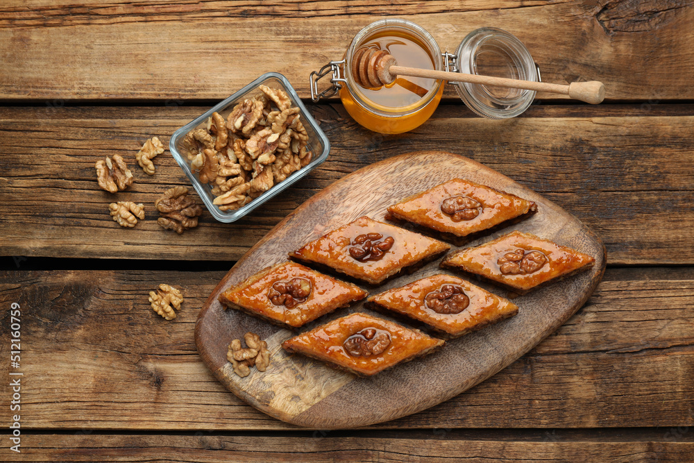 Delicious sweet baklava with walnuts and honey on wooden table, flat lay Delicious sweet baklava with walnuts and honey on wooden table, flat lay
