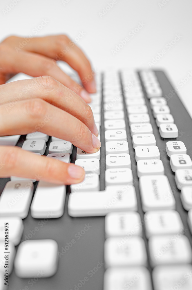 Female hands are typing on a white keyboard of a personal computer. Female hands are typing on a white keyboard of a personal computer.