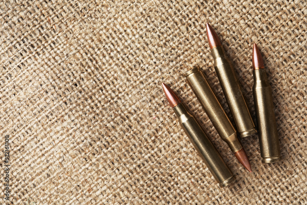 Many brass bullets on burlap, flat lay. Space for text Many brass bullets on burlap, flat lay. Space for text
