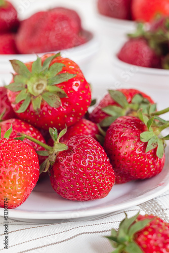 A white plate with fresh red strawberries.