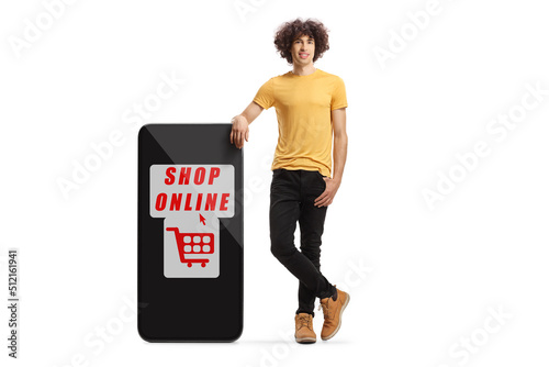 Young man with curly hair stanging next to a smartphone with text shop online photo