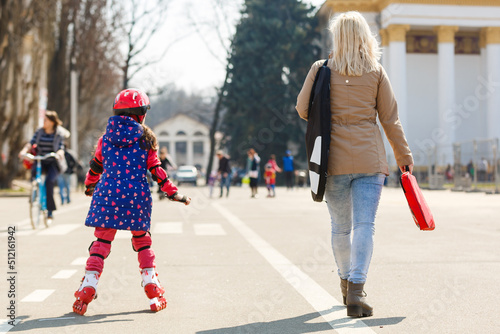 Caucasian woman teaches her daughter to skate on roller skates