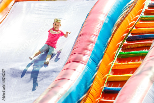 Happy little girl having lots of fun on a jumping castle during sliding.