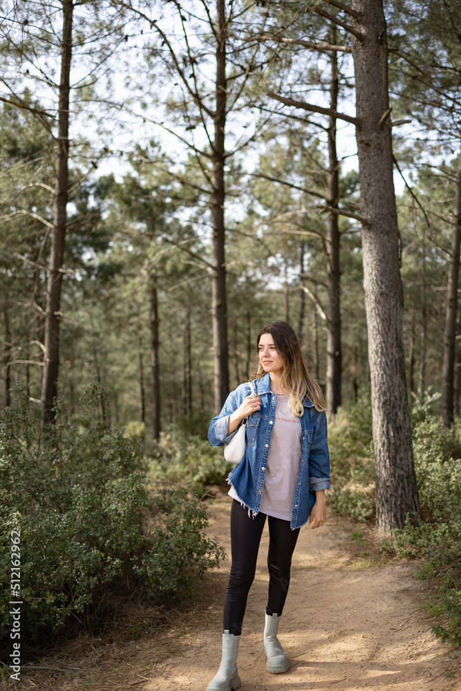 Beautiful young woman in forest. She wears a jean jacket. Beautiful young woman in forest. She wears a jean jacket.