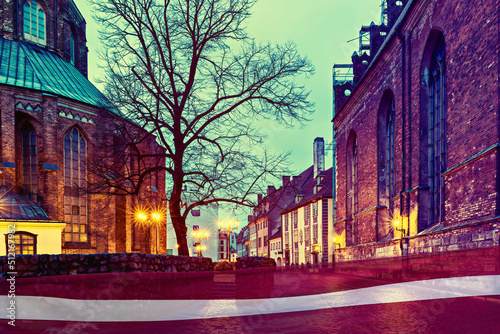 Night view of the old Riga town. Flag of Latvia on foreground