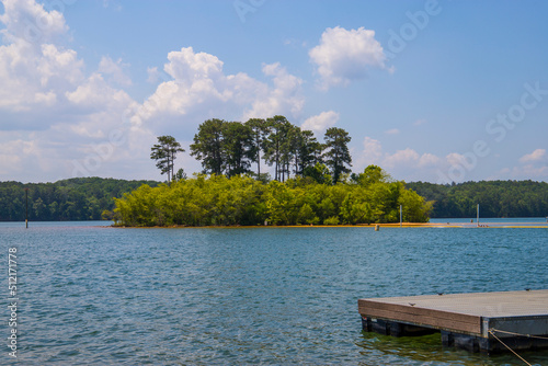 a gorgeous summer landscape at Lake Allatoona with rippling blue lake water surrounded by lush green trees, grass and plants with blue sky and clouds at Victoria Beach in Acworth Georgia USA photo
