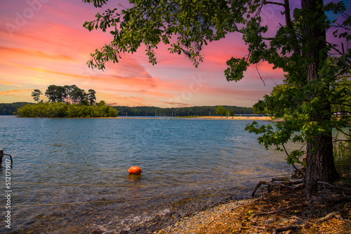 a gorgeous summer landscape at Lake Allatoona with rippling blue lake water surrounded by lush green trees, grass and plants with powerful clouds at sunset at Victoria Beach in Acworth Georgia USA photo