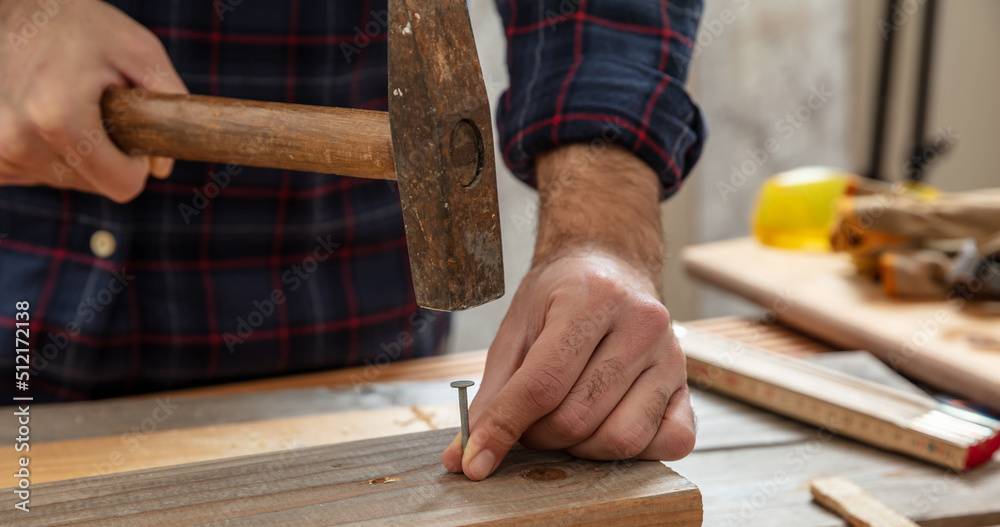 Carpenter nail wood. DIY, home repair and fix. Male hand hold hammer and nail.