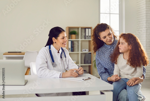 Young mother and small child at appointment with pediatrician in hospital. Caring mom take little daughter to private clinic, talk with doctor about symptoms. Children healthcare concept.