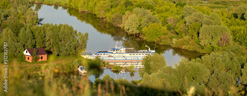  A small cruise ship at the pier in a picturesque place of the river in the soft light of the setting sun. photo
