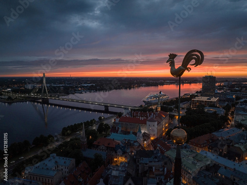 Fotografia Symbol of old Riga town - golden cockerel, rooster topping bell tower of Riga Doms Cathedral at sunset