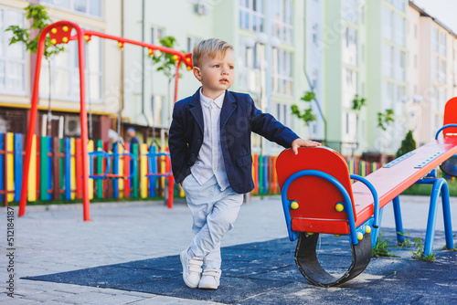 A little boy 2 years old in a shirt and jacket stands on the street. Children's classic costume for the holiday. Children's fashion. photo