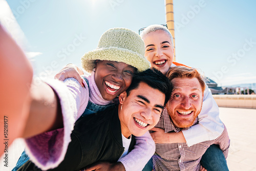 Group of friends giving piggyback ride to girlfriends. Happy young friends enjoying a weekend day.