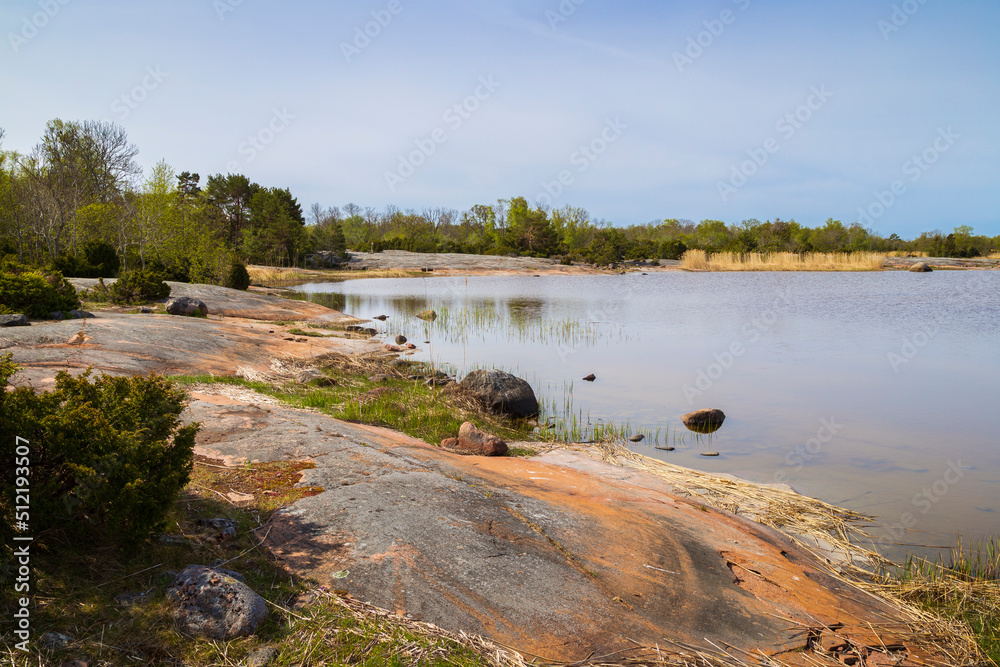 View of cliff, sea and lush shoreline along the nature trail at the Järsö nature reserve in Åland Islands, Finland, on a sunny day in the summer.