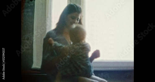 Happy mother having fun with laughing child in room. Cheerful young woman hugging Smiling baby girl near window home. Fanny family life indoors. Vintage color film. Family archive. Retro 1980s. 4k