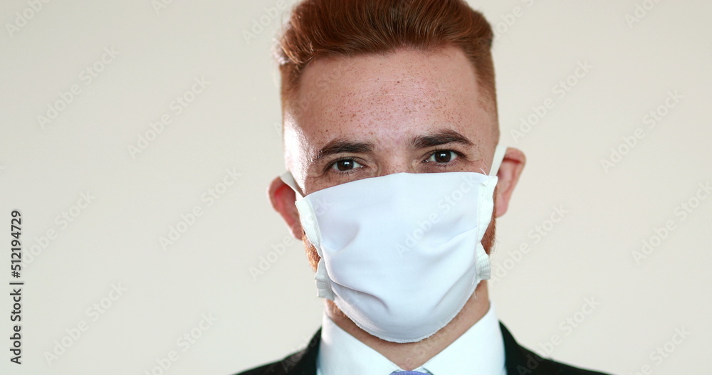 Business man putting on covid-19 mask looking at camera Business man putting on covid-19 mask looking at camera