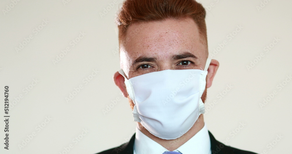 Business man putting on covid-19 mask looking at camera Business man putting on covid-19 mask looking at camera