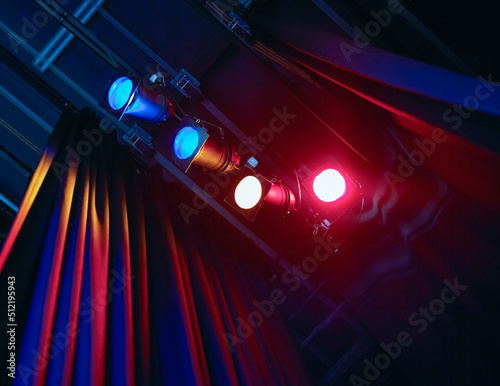 Coloured spotlights shining past curtain in theatre photo