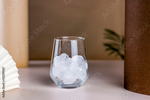 The Glass with ice cube on pastel color abstract background. Empty transparent water glass for your cold drinks.