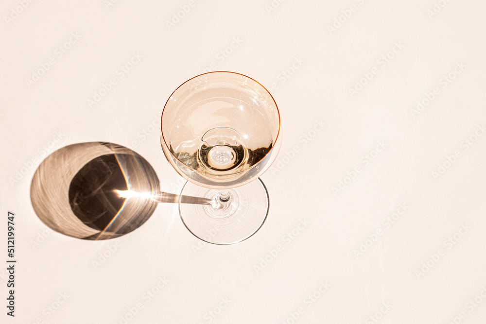 Cocktail glass with drinks on the light table in natural sunlight with shadows. Minimalist creative summer drinks composition. Flat lay, top view image. Cocktail glass with drinks on the light table in natural sunlight with shadows. Minimalist creative summer drinks composition. Flat lay, top view image.