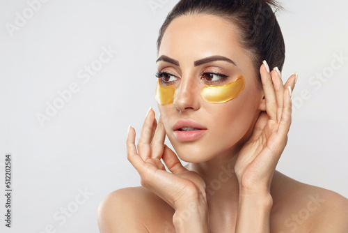 Photo Beautiful woman with gold patches for eyes on a grey background