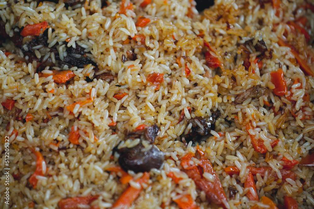 Cooking rice, pilaf in a cauldron. The concept of cooking street food. Juicy beef pilaf is cooked in a cauldron on the street in close-up. Red and yellow rice. Close up of a pile of rice. Cooking rice, pilaf in a cauldron. The concept of cooking street food. Juicy beef pilaf is cooked in a cauldron on the street in close-up. Red and yellow rice. Close up of a pile of rice.