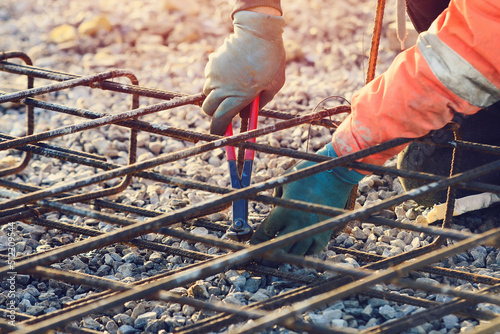 Foto Builder's hands fixing steel reinforcement bars at construction site