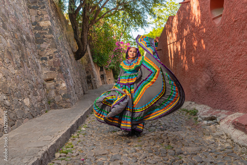Young Mexican woman in a traditional folklore dress of many colors, traditional dancer.