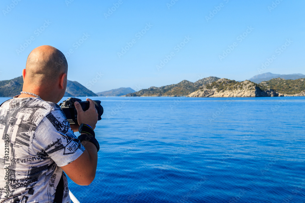 Obraz premium Travel photographer man with professional camera taking photos of the Mediterranean Sea in Antalya province, Turkey