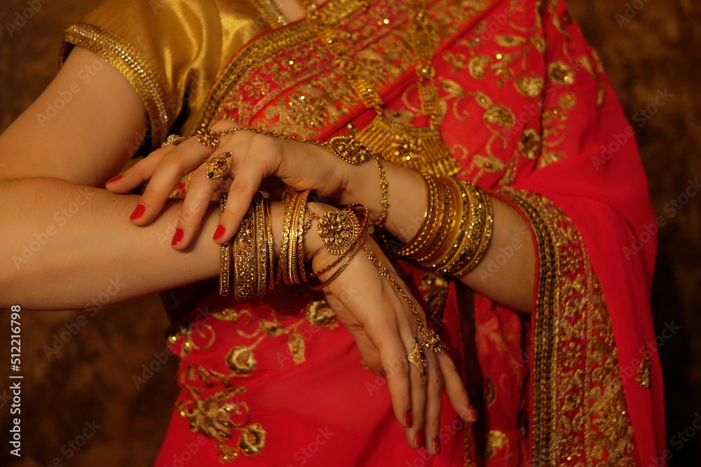 Hands of an indian bride close-up. Lots of jewelry, traditional sari.