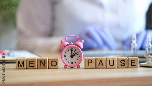 Word menopause collected of wooden cubes in raw and pink alarm-clock