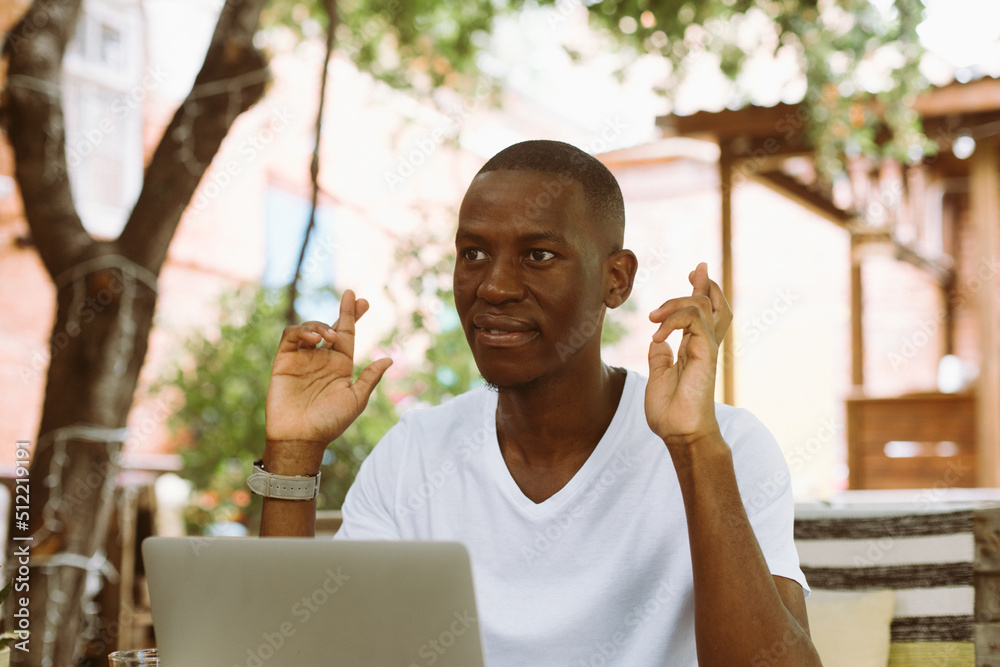 Smiling african american businessman working on laptop in the street ...