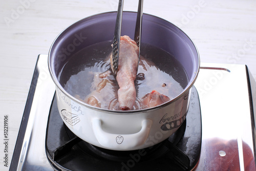 Indonesian Home Cooking Process, Female Hand Add Chicken Thigh Drumstick to the Pan using Tongs, Making Indonesian or Thai Style Curry, Traditional Asian Gourmet Called Opor Ayam