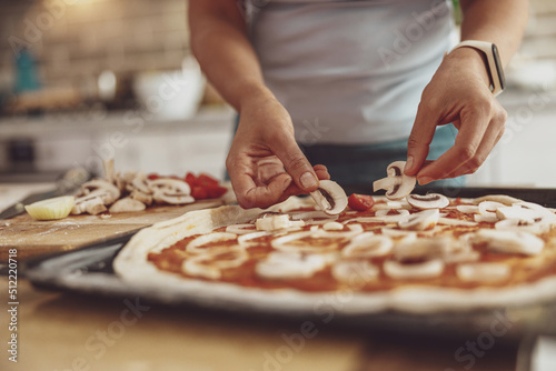 A woman spreads mushrooms on a homemade pizza before baking in the oven