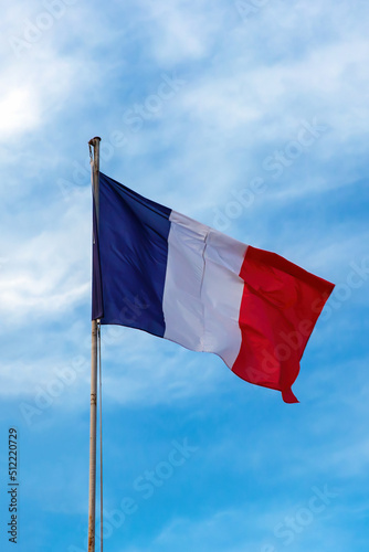 French flag on blue cloudy aky background.