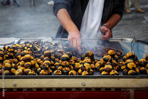 The cook roasts chestnuts in a kiosk on the street.