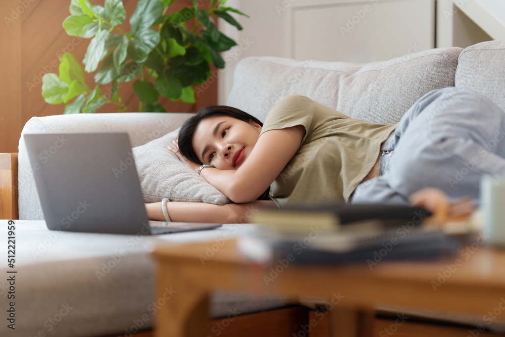 Portrait of Happy Beautiful woman lay down on cozy couch and listen music by streaming on laptop. Portrait of Happy Beautiful woman lay down on cozy couch and listen music by streaming on laptop.