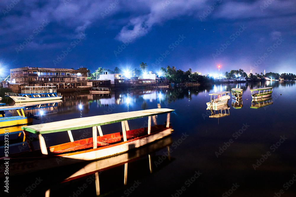 boats at night in lake with reflections on the water and dark sky in coyuca lagoon, pie de la cuesta, acapulco guerrero 